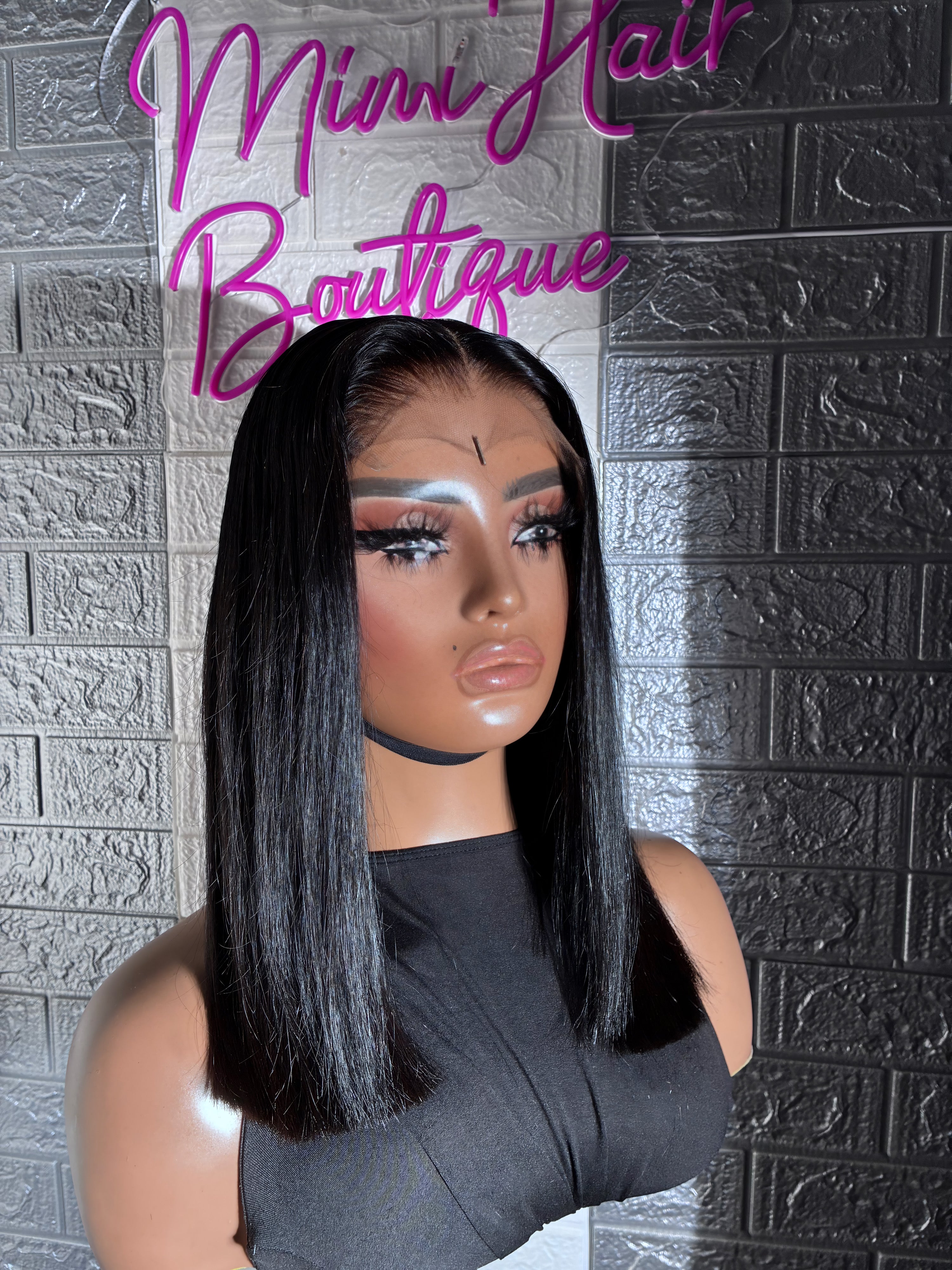 Mannequin head with a black wig against a textured gray wall with 'Mimi Hair Boutique' text.