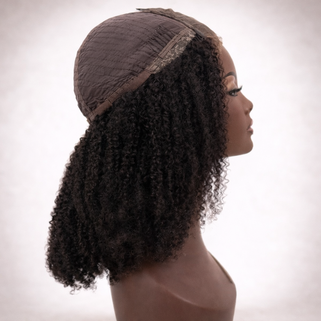 Mannequin head with a brown curly wig on a plain background