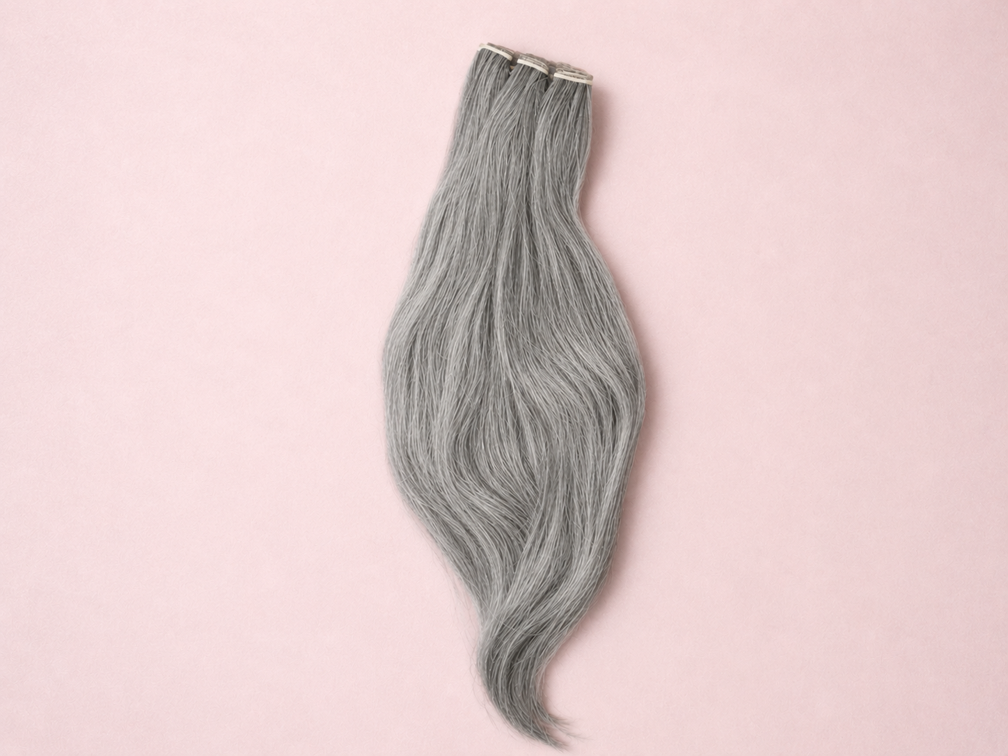 Gray hair extensions on a pink background