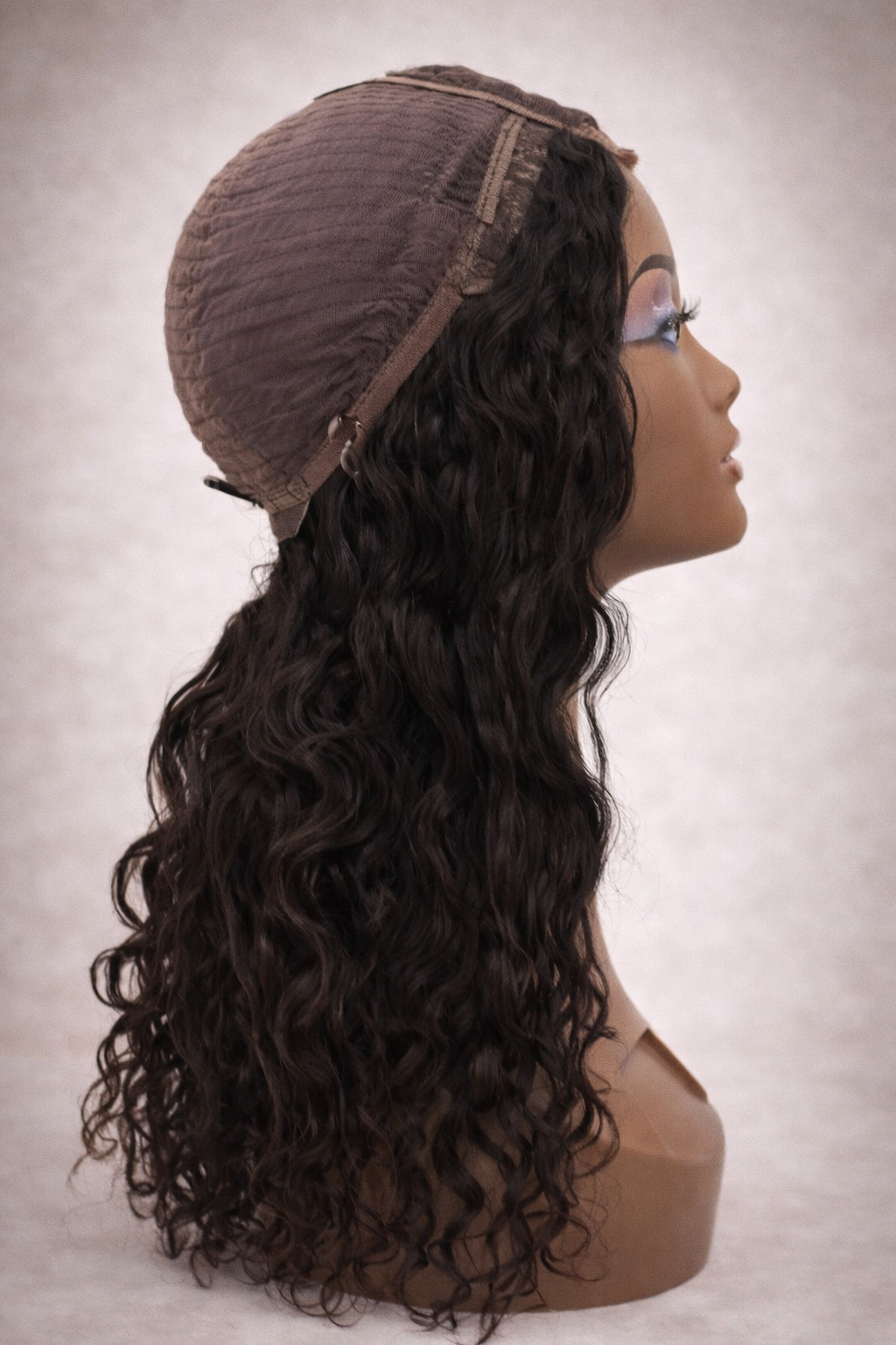 Mannequin head with a brown wig on a plain background